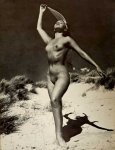 Solo nude woman lifting fabric over head on beach